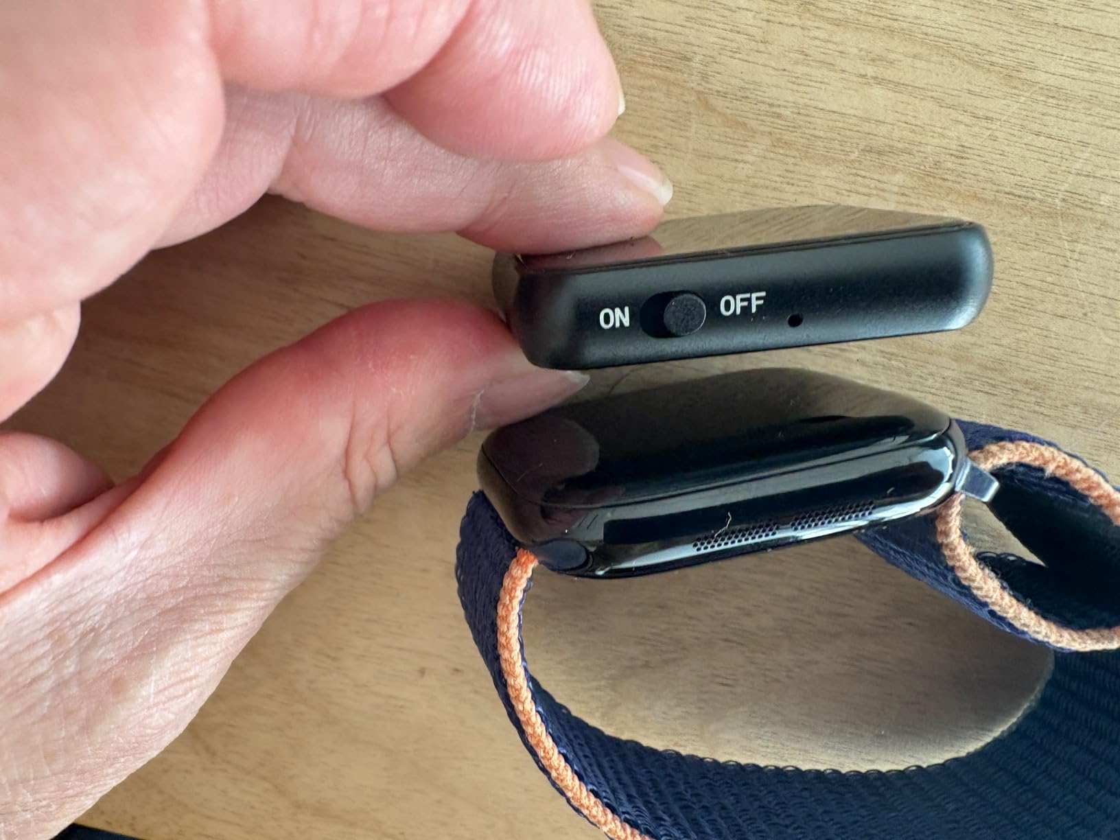 A sleek round mini voice recorder resting on a wooden office desk