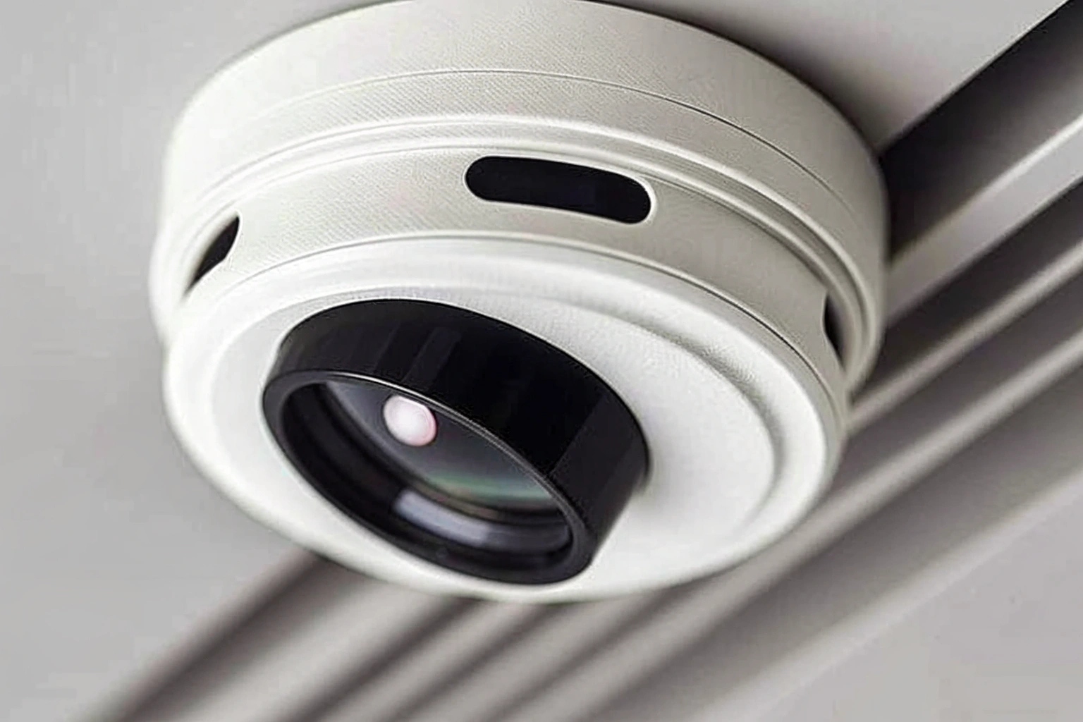A close-up of a smoke detector with a tiny, suspicious black dot indicating a hidden camera lens.