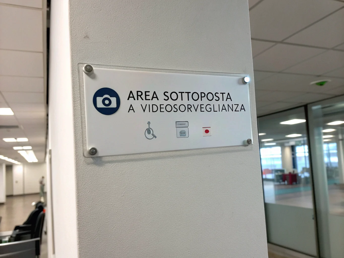 Un cartello di avviso "Area Sottoposta a Videosorveglianza" affisso su un muro di un ufficio, a norma di legge