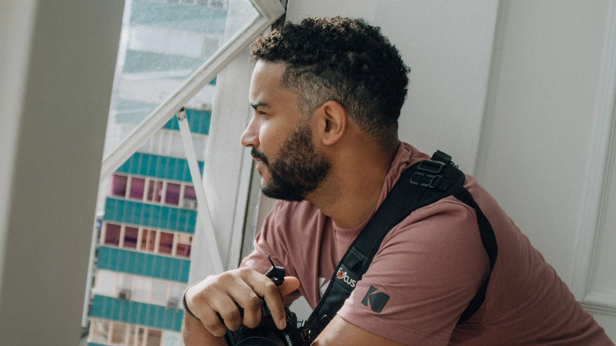 Person with a camera looking through an indoor window in daylight