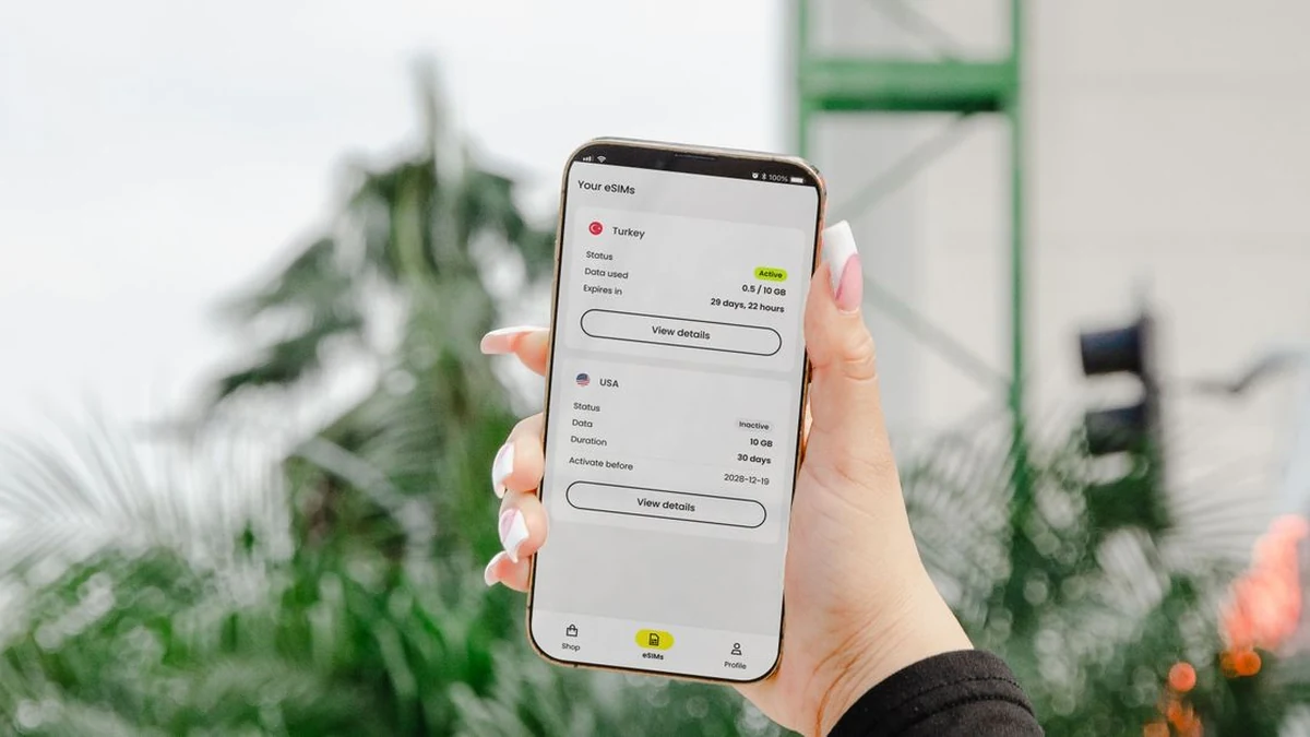 Hand holding a smartphone with an eSIM data-plan interface outdoors