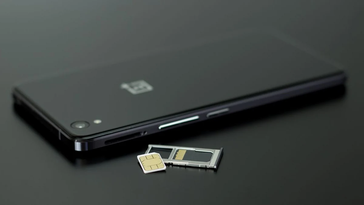 Smartphone with SIM card and memory card on a dark tabletop