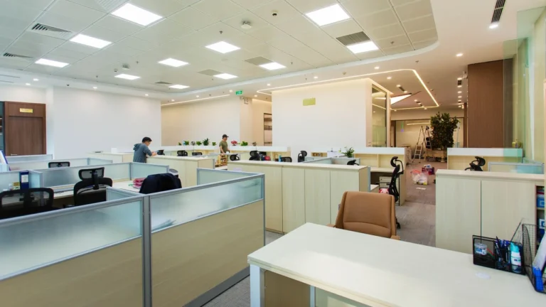 Open-plan office with ceiling lights, desks and windows