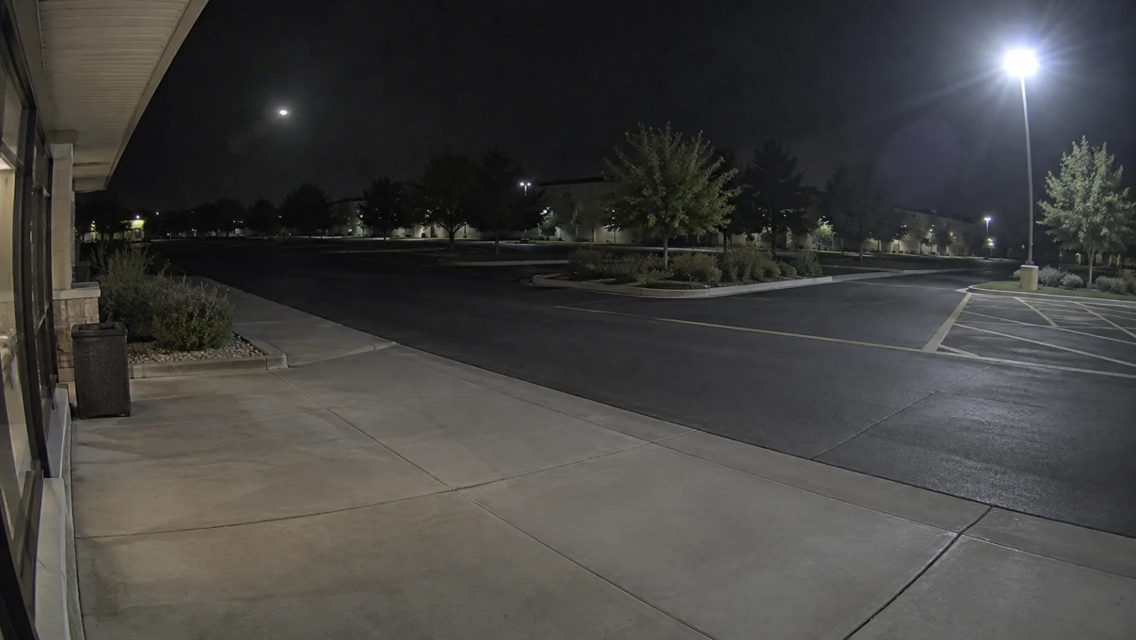Outdoor security camera view with a bright streetlight and a faint reflected light ghost